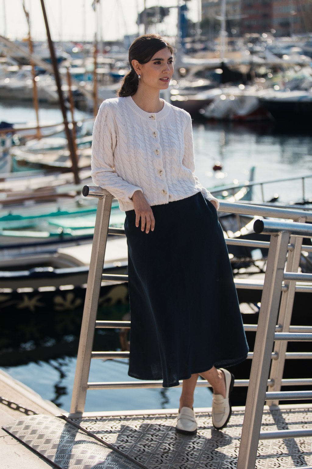 Valkoinen palmikkoneuletakki sekä tummansininen midipituinen puuvillahame