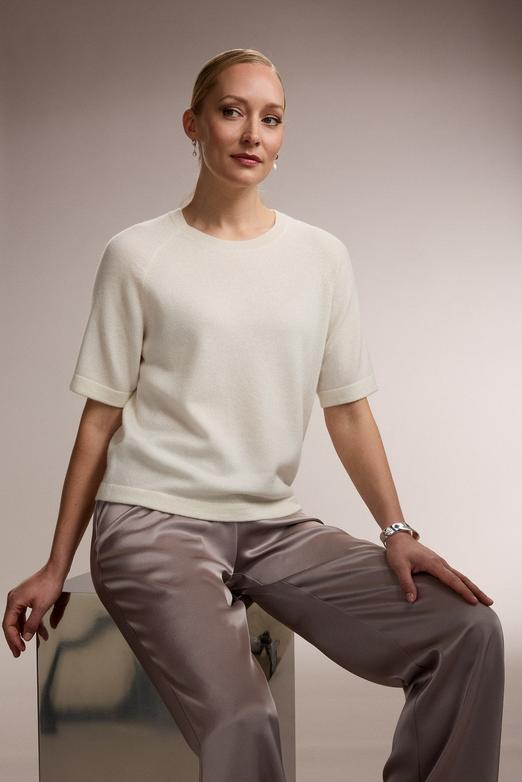 Nainen, jonka päällä on sileä valkoinen kashmirneule.