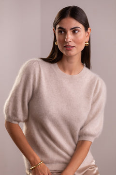 Nainen, jonka päällä on Original Storyn lyhythihainen puhvihihallinen kashmirneule sävyssä latte