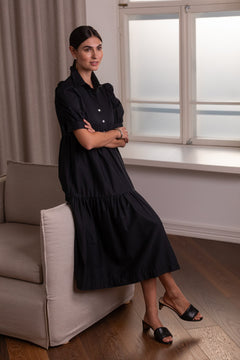 Nainen, jonka päällä Original Storyn musta puhvihihallinen puuvillasekoitemekko.